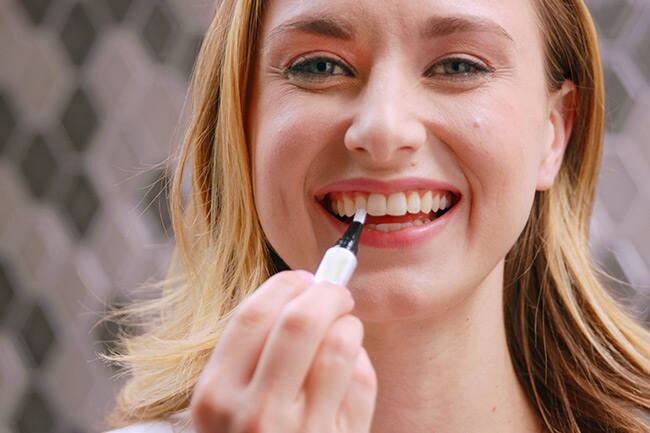 Young woman using Express Teeth Whitening Pen
