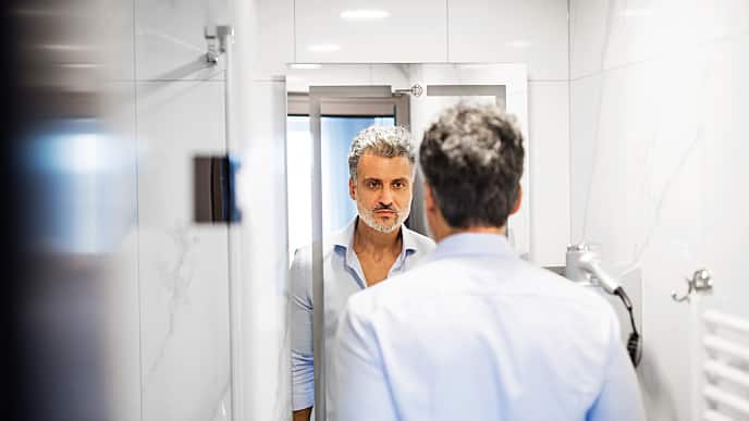 Older man looking at himself in the mirror