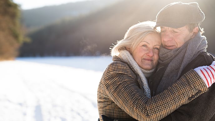 L'image est d'une femme plus âgée étreignant un homme plus âgé - serré ensemble dans la neige et les montagnes.