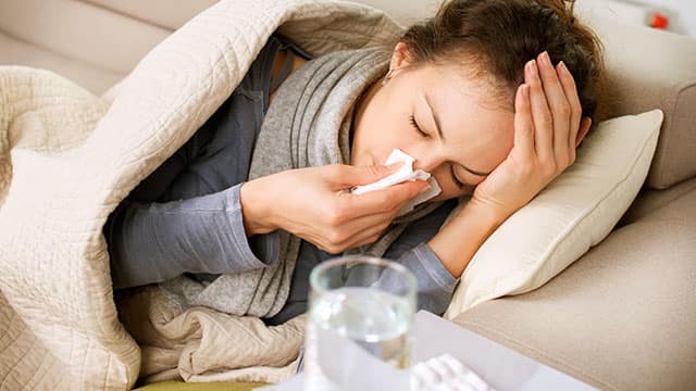 Woman in a bed sneezing in to the tissue