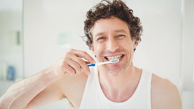 Hombre con sonrisa perfecta lavándose los dientes