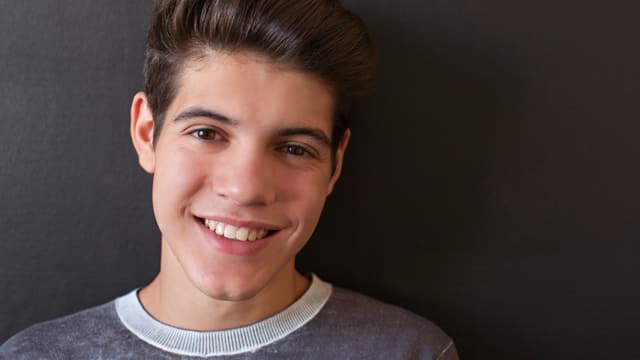 Joven con camisa gris sonriendo Joven con camisa gris sonriendo