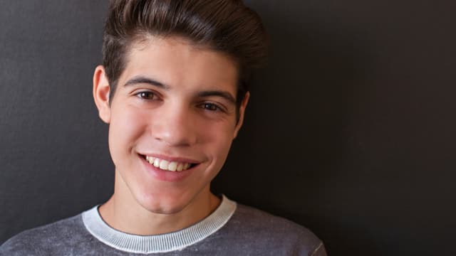 Joven con camisa gris sonriendo