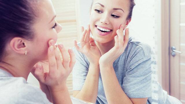 A woman is looking in to the mirror in a bathroom