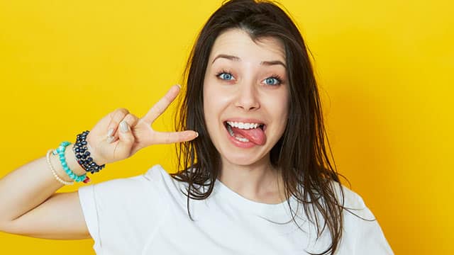 Young woman showing her tongue and a victory sign