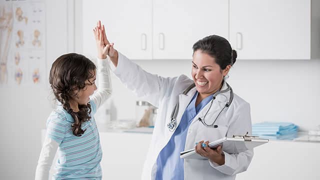 A female doctor and a child hi-five each other