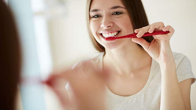 Young woman is brushing her teeth