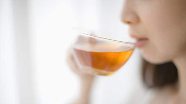 A woman is drinking tea from glass cup