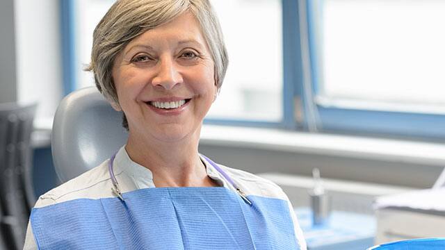 an older woman smiling in a dental chair