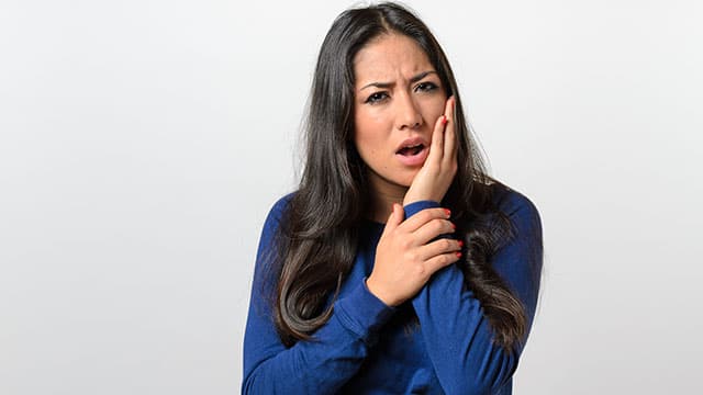 A woman holding her hand to the cheek because of the toothache