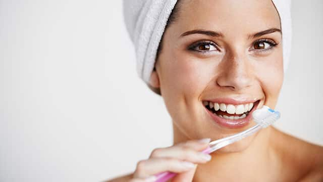 A woman is brushing her teeth in the bathroom