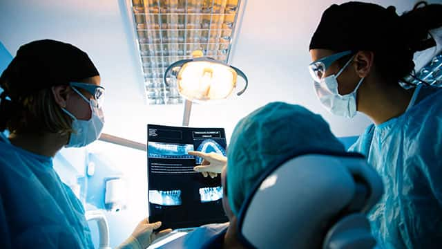 Two dentists discuss an x-ray with a female patient