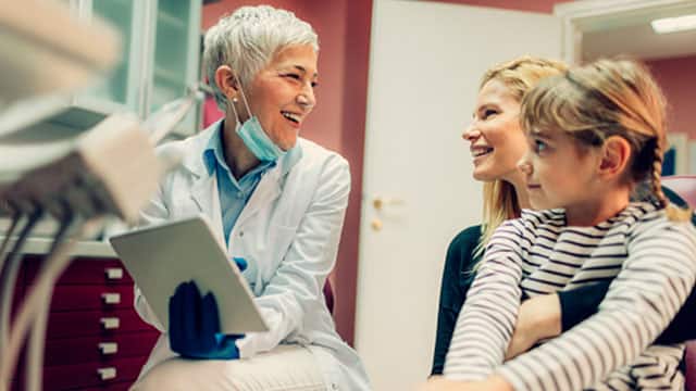 A female dentist an mother with the daughter in the dental office A female dentist an mother with the daughter in the dental office