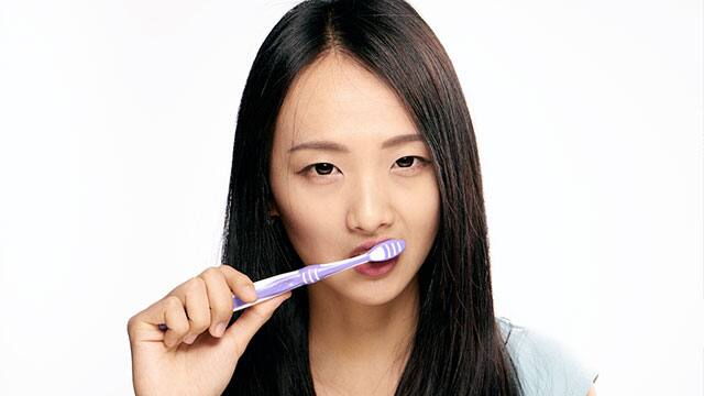 Asian woman is brushing her teeth