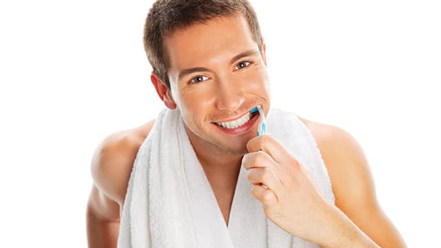 A man is brushing his teeth indoors