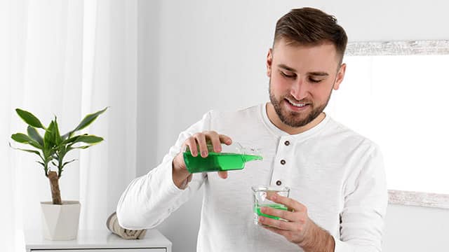 A man is pouring a mouthwash in to the glass 