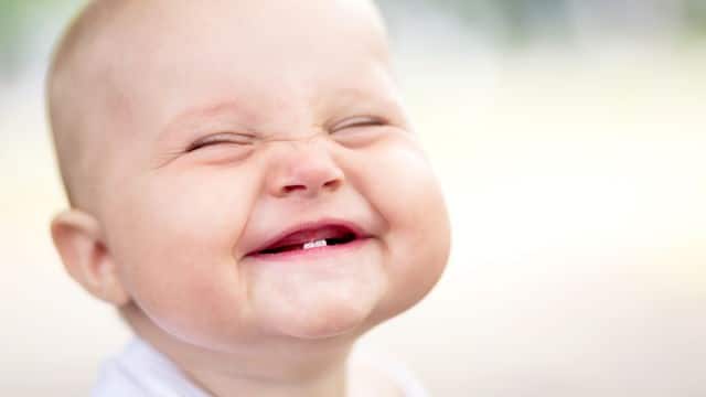 a baby with first tooth smiling brightly