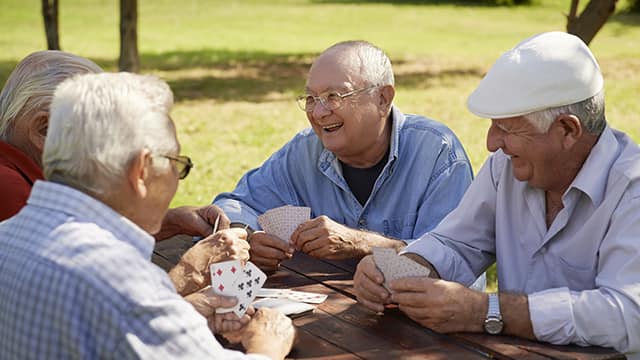 Adultos mayores jugando cartas y sonriendo