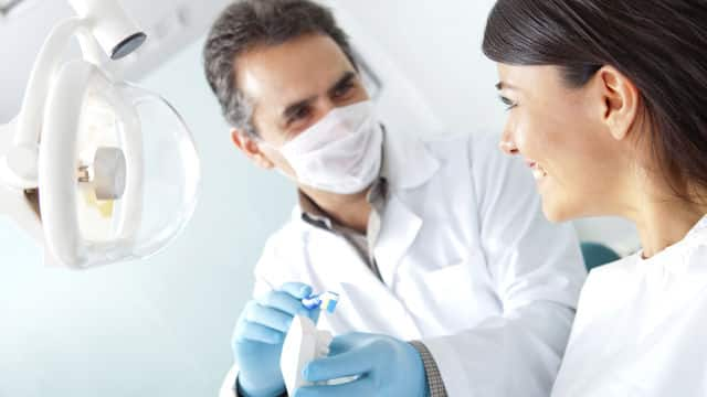 Dentist demonstarting brushing procedure to a patient