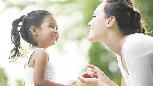 a mother smiling while looking at her daughter smiling