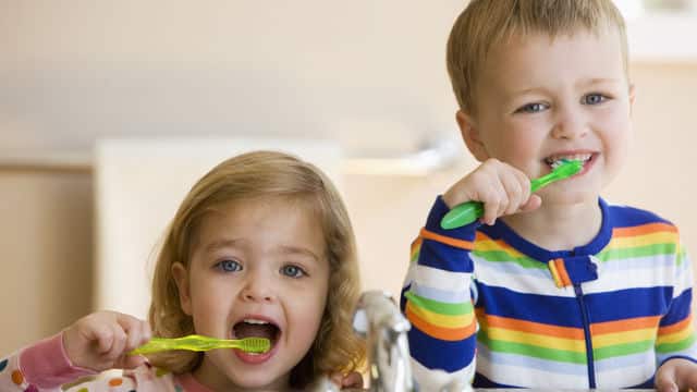 a boy and a girl brushing their teeth with Colgate toothbrush