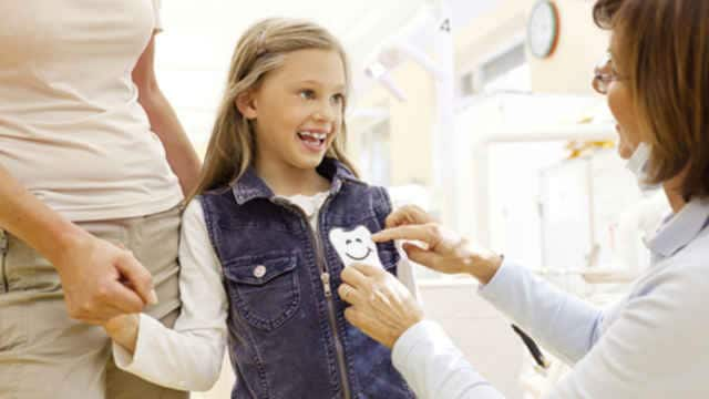 Niña sonriendo a su dentista en el consultorio