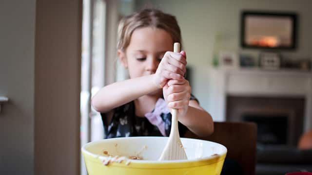 girl holding a spatula mixing cookie batter