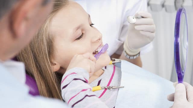 a girl brushing her teeth at the dentist