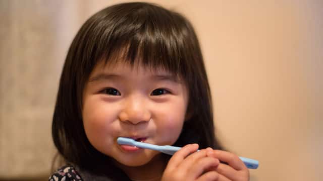 young girl brushing her teeth with Colgate toothbrush