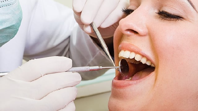 a female is being checked by dentist if she has oral cancer or gingivitis