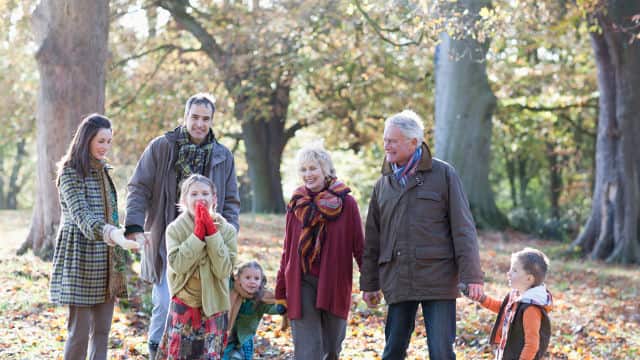 grandparents with their child and grandchildren smiling brightly walking outdoor