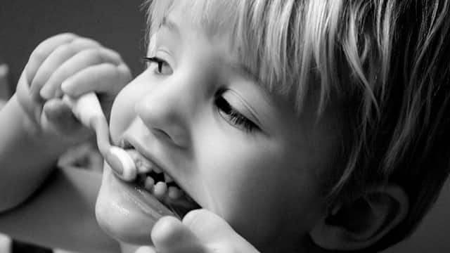 boy brushing his teeth with Colgate toothbrush
