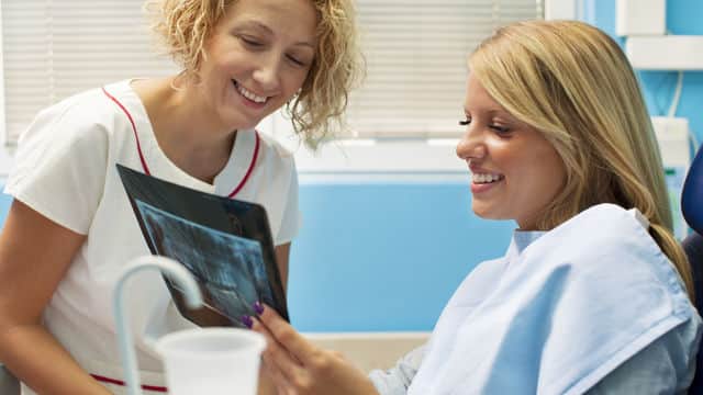 Patient looking over her dental x-ray with the dentist assistant