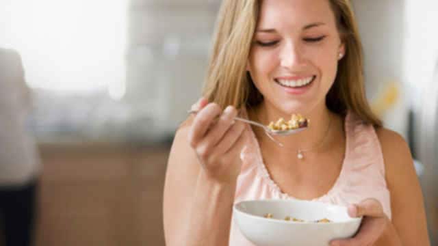 woman smiling while eating a bowl of cereal