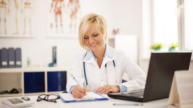 dentist smiling while writing notes on the chart