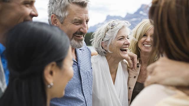 older couple near mountains laughing with friends