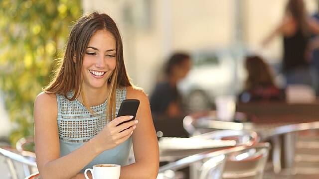 a girl is looking for the causes of a swollen gum around on tooth on her phone with smile