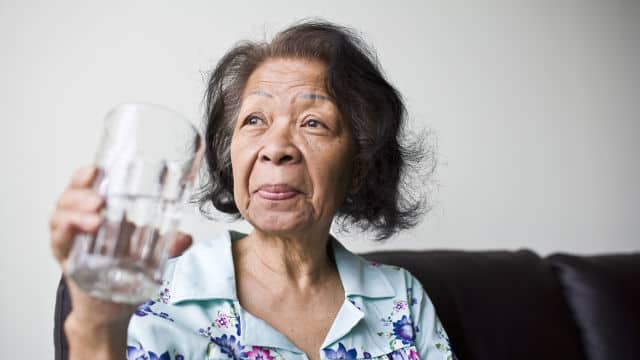 an elderly woman holding a glass of water