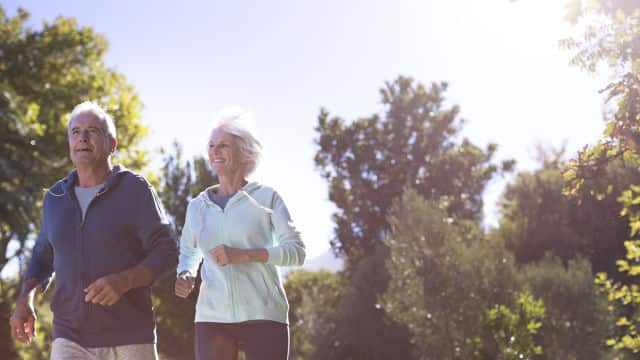 an elderly couple smiling while jogging