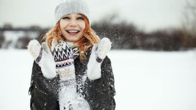 Girl playing with snow outdoors happily