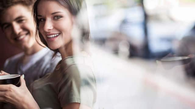 a man and a woman smiling while enjoying a cup of coffee