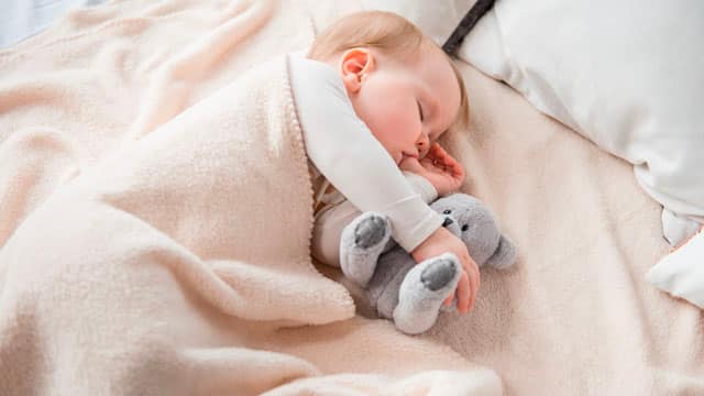 A sleeping baby sucking their thumb.