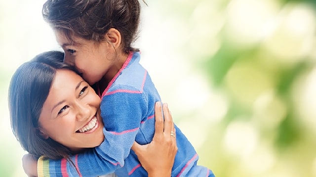 a mother smiling while holding her daughter