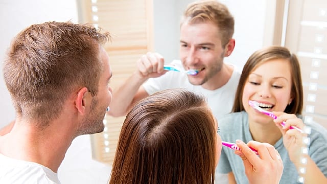 A young couple are brushing teeth in the bathroom together
