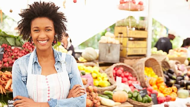 Mujer sonriendo en un mercado de frutas