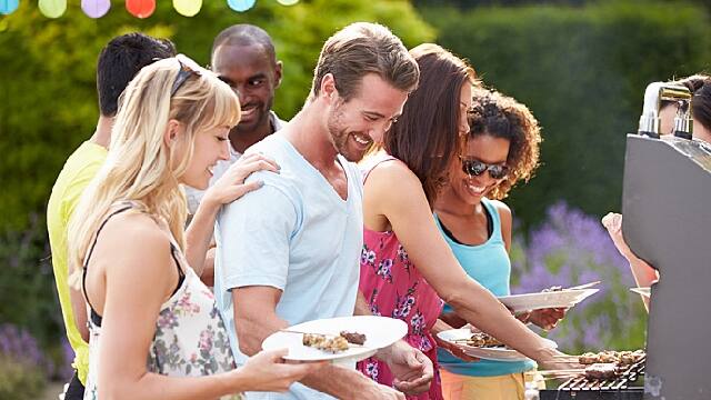 a group of friends smiling while having a barbecue