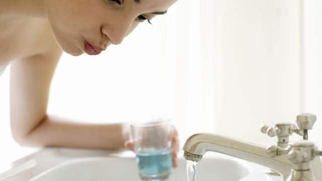 woman gargling mouthwash in the sink