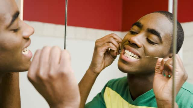 a young male is flossing his teeth in the bathroom