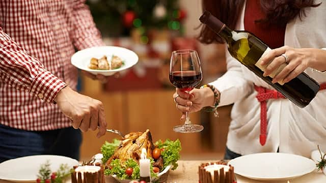 Woman pouring wine and a man fixing a plate of food