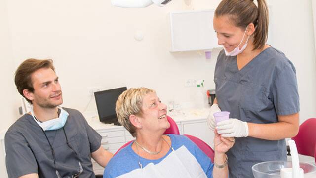 A middle-aged woman sitting in a dentist's chair.